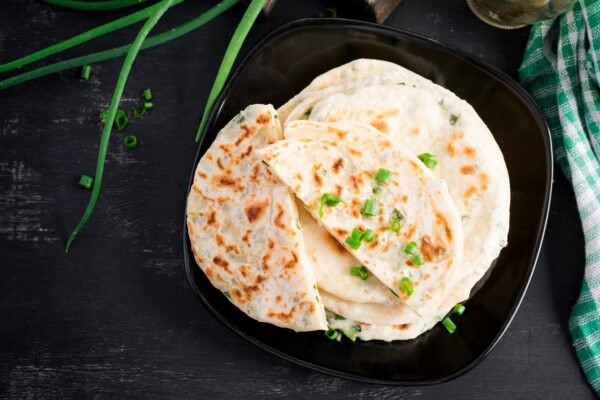 Traditional indian bread. Pita bread with green onions. Onion naan. Top view